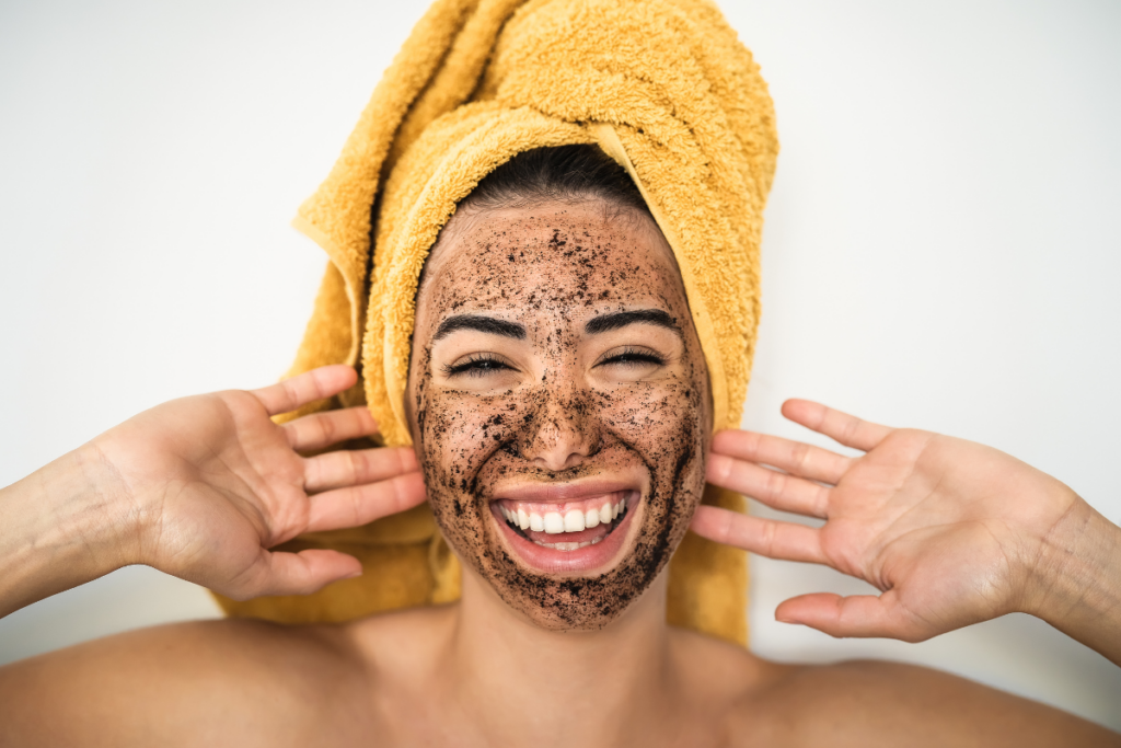 Happy woman exfoliating with coffee grounds