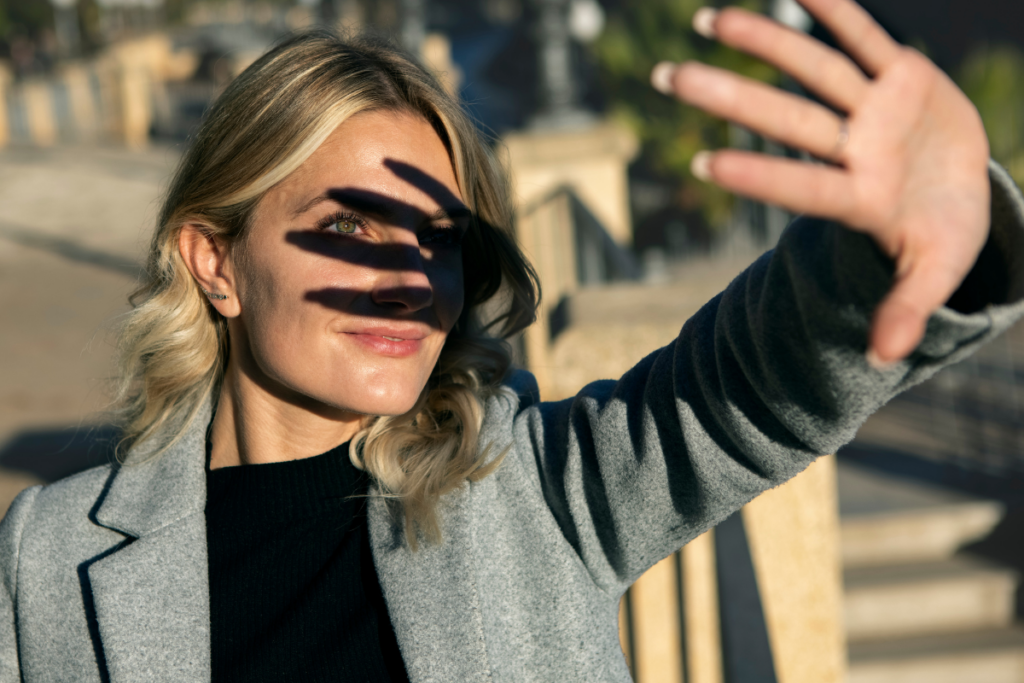 Woman shielding face from sun as an image of sun damage