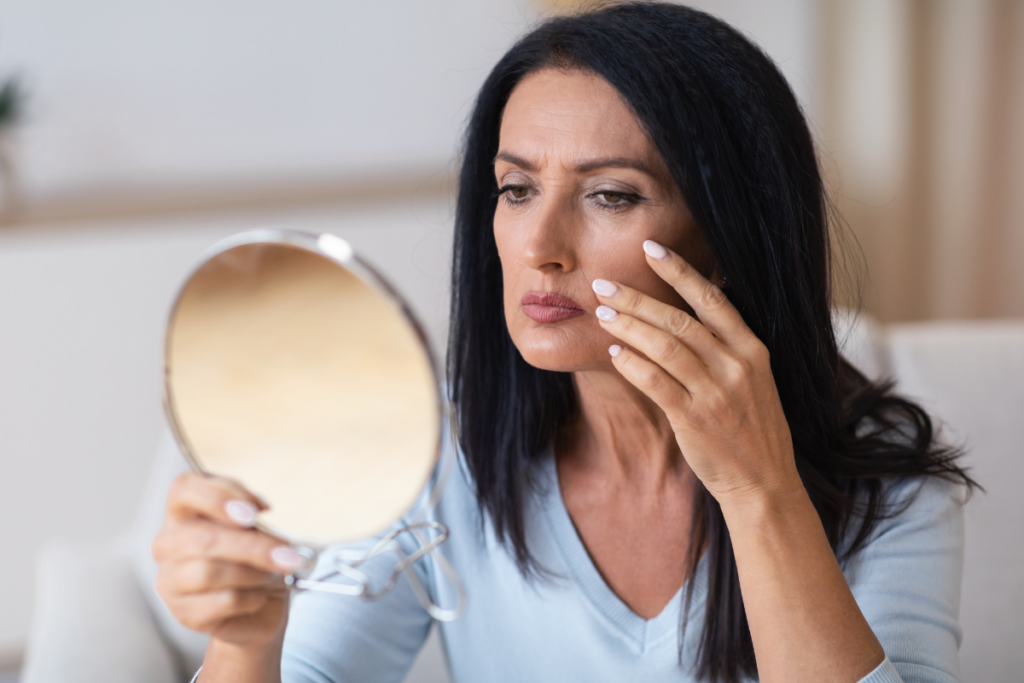 mature woman looking at face and skin in mirror