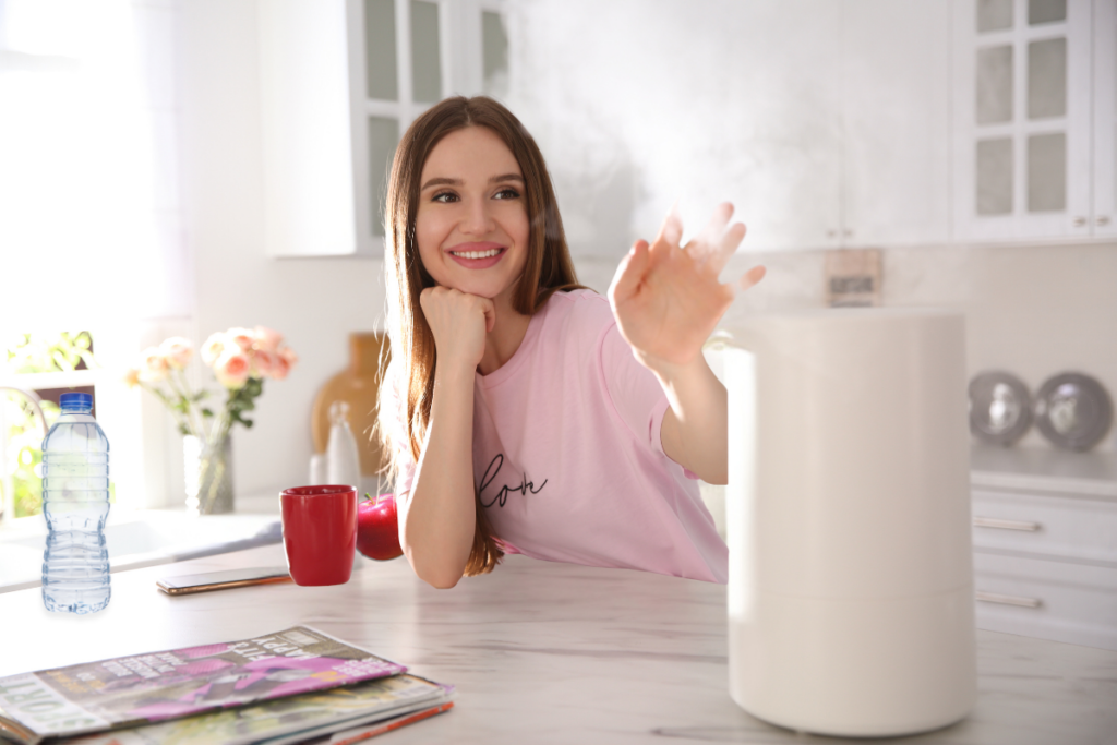 Woman with beautiful skin in kitchen with humidifier and water bottle