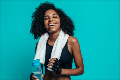 Happy woman with beautiful skin holding water bottle after workout