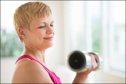 Mature woman with glowing skin working out with dumbbells