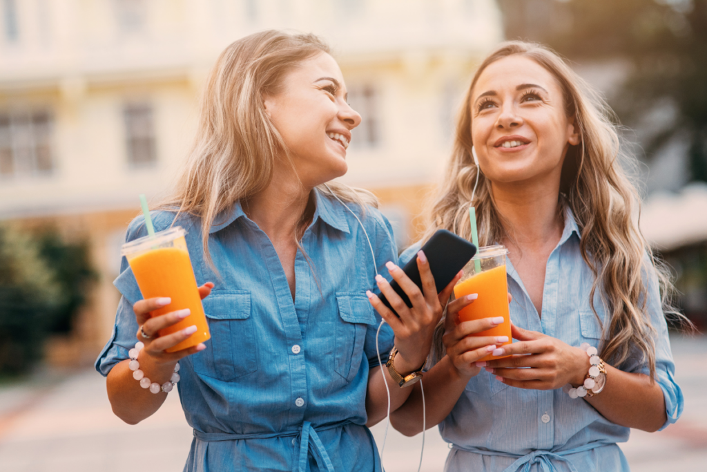 Two women with juice drinks and enjoying Dry January benefits for their skin