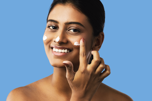 Young, happy woman applying moisturizer and taking care of her skin