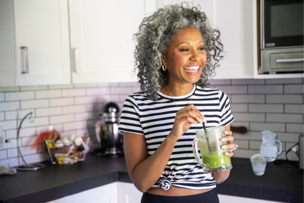 A healthy, happy, vibrant woman drinking a green smoothie