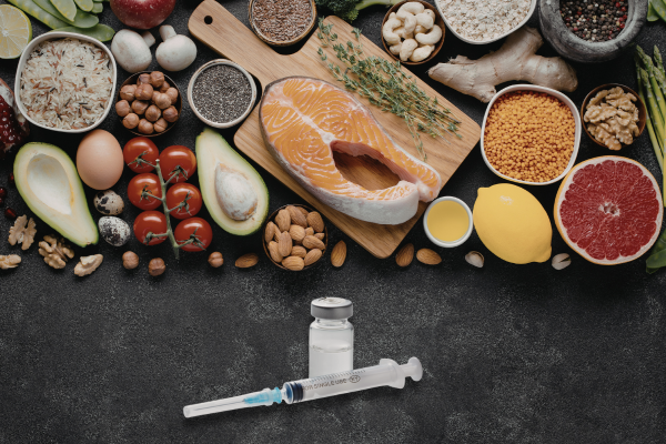 Nutrient-dense foods, including salmon, avocados, and nuts above a vial and syringe