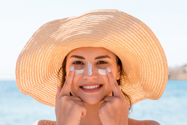 Woman wearing wide-brimmed hat with sunscreen on her face