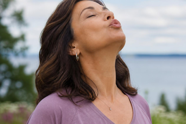 Woman performing a _kiss the sky_ stretch for natural neck tightening