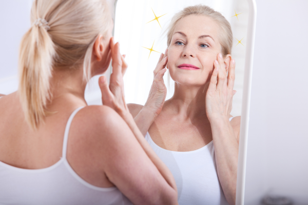 A mature woman with beautiful skin looking in the mirror; image obtained here_ https___www.canva.com_photos_MADerwuM1vs
